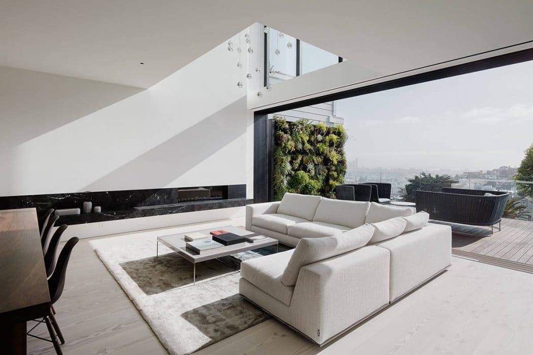 Luxurious modern living room with sleek white sofa, floor-to-ceiling windows, and panoramic city views, featuring contemporary interior design and stylish outdoor seating area.