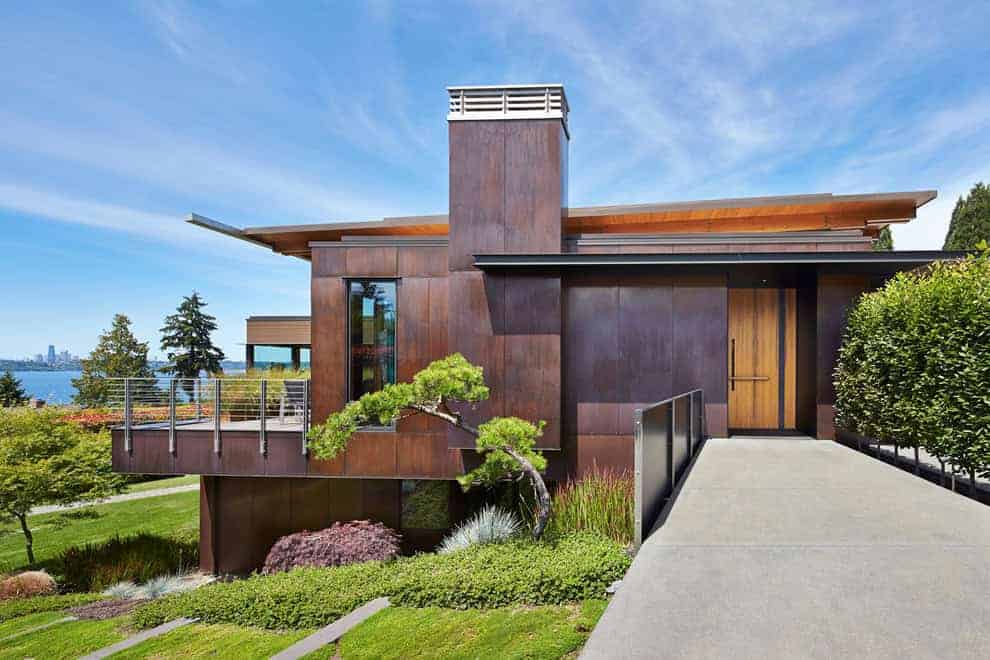 Contemporary modern house with wooden exterior, lush landscaping, and scenic waterfront view, showcasing innovative architecture and stylish design.