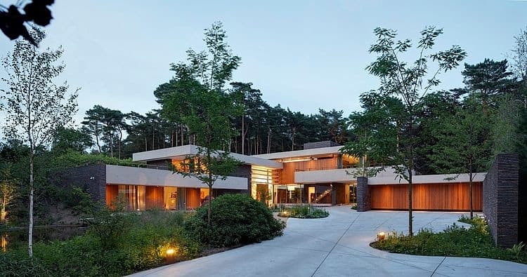 Contemporary modern house design with sleek architecture and expansive glass windows, surrounded by lush greenery and landscaping.