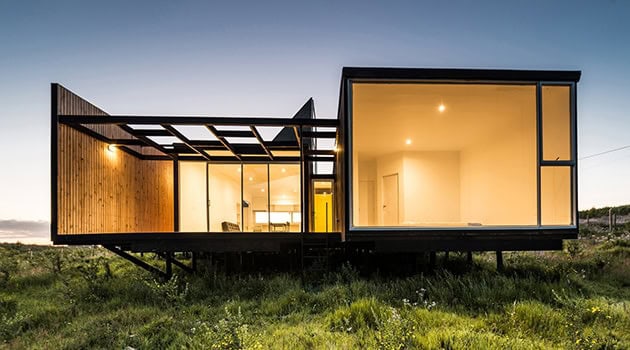 Contemporary modern house with large glass windows and minimalist design set in a natural landscape, showcasing innovative architecture and sustainable building materials.