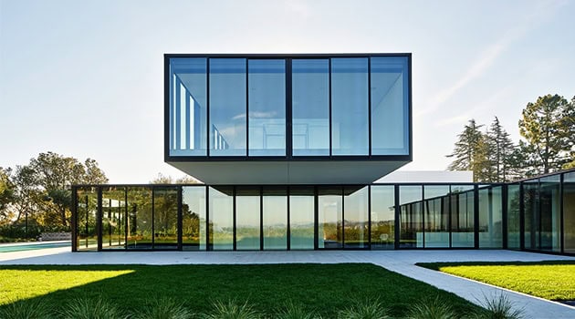 Sleek modern glass house with minimalist architectural design and expansive windows showcasing contemporary luxury living.