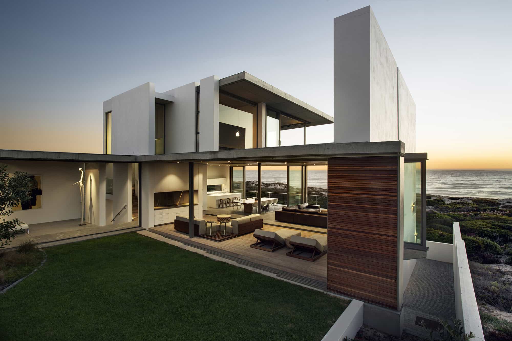 Modern coastal minimalist house with open concept living space, large glass windows, and ocean views, showcasing contemporary architecture design and stylish outdoor terrace.