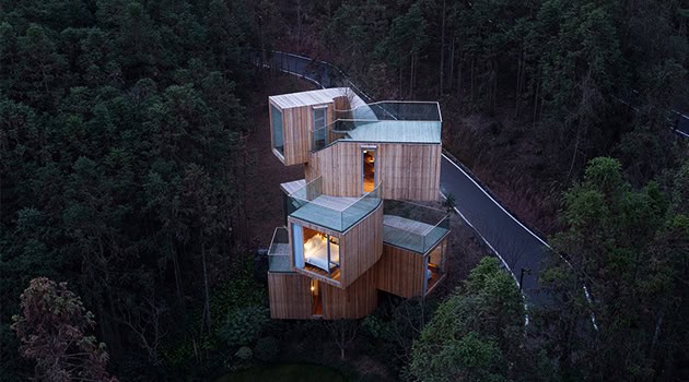 Stunning modern treehouse with cubic architecture, glass walls, and wooden exterior set in a lush forest environment. Perfect for modern architectural design and upscale nature retreats.