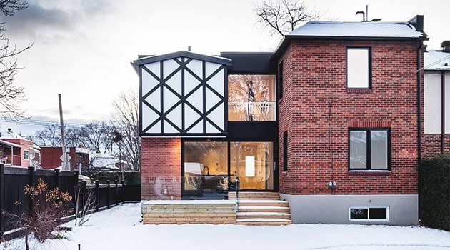Modern brick house with black and white geometric facade, large glass windows, and snow-covered landscape, showcasing innovative architecture and contemporary residential design.