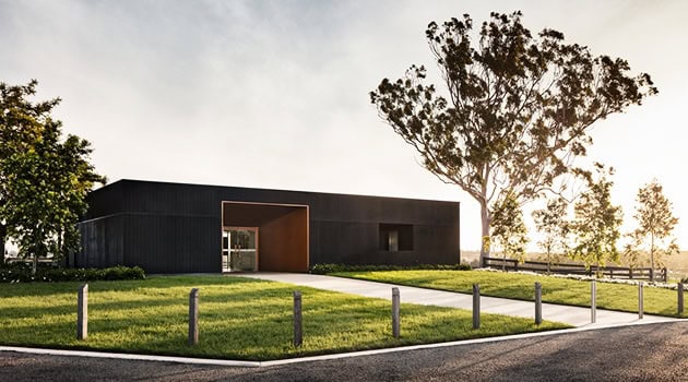 Modern minimalist black house with clean lines and open space, surrounded by greenery, showcasing innovative architectural design & contemporary home architecture.