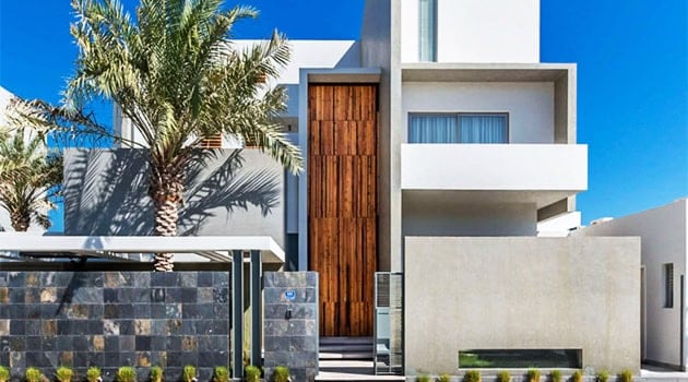 Modern minimalist house with clean lines and contemporary architecture featuring white and concrete facades, wooden accents, and lush palm trees for elegant residential design.