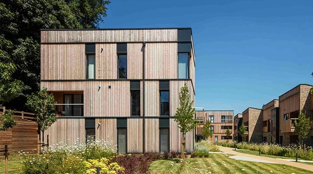 Modern wooden residential buildings with eco-friendly design and spacious green landscaping in a contemporary neighborhood setting.