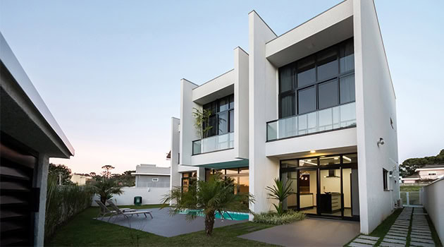Modern white architectural villa with large glass windows and an outdoor pool, showcasing contemporary luxury home design and stylish landscaping.