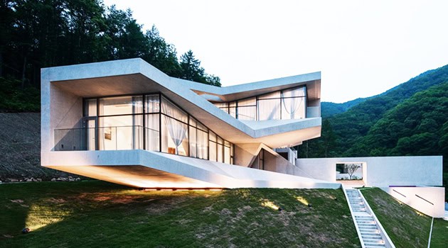 Contemporary modern house with geometric design and extensive glass windows in a scenic mountain setting, exemplifying innovative architecture art design.