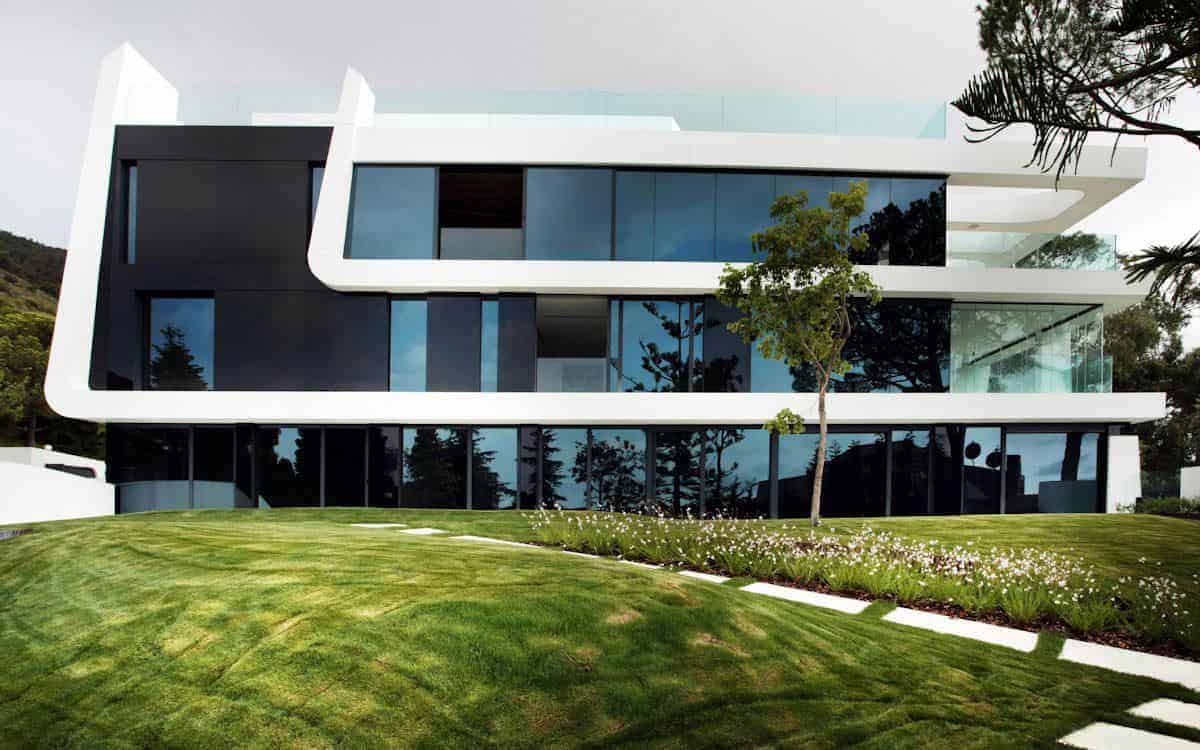 Modern minimalist house with sleek black and white architectural design, large glass windows, and landscaped garden, exemplifying contemporary residential architecture.