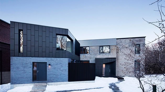 Modern contemporary house with sleek black and grey exterior finishes, large windows, and minimalist design elements in a snowy landscape.
