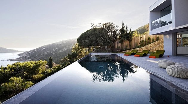 Luxurious modern hillside infinity pool overlooking scenic landscape with stylish outdoor seating area, contemporary architecture, and panoramic views.