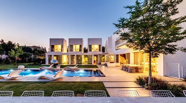 Modern luxury villa with sleek architecture, an outdoor pool, and contemporary design featuring spacious patios and lush greenery.