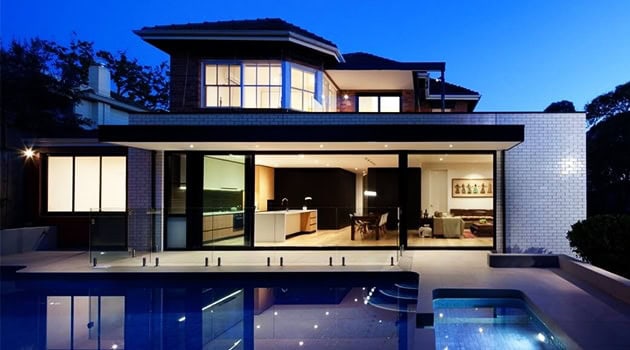 Modern luxury house with glass walls, swimming pool, and contemporary interior design at dusk.