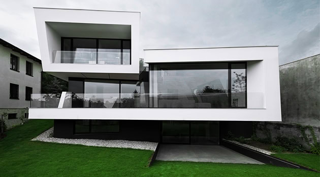 Sleek modern white and black minimalist residential building with large glass windows and balconies, showcasing contemporary architectural design and innovative structural elements.