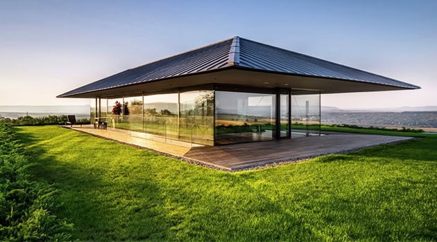 Modern glassitecture home with sleek design, expansive windows, and contemporary style, set in a lush green landscape featuring minimalist architecture and eco-friendly features.