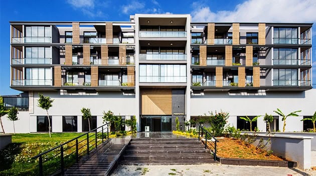 Contemporary multi-story residential building with modern architectural design, large glass windows, and landscaped surroundings, showcasing innovative urban apartment architecture and design.