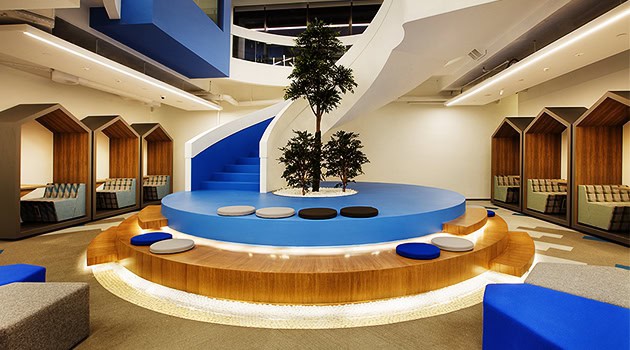 Vibrant modern interior with circular seating area, central indoor trees, and innovative spiral staircase, showcasing contemporary architecture and creative design elements for inspiring spaces.