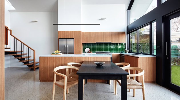 Modern kitchen interior with minimalist design, wooden cabinetry, green tiled backsplash, large window for natural light, and contemporary dining area.