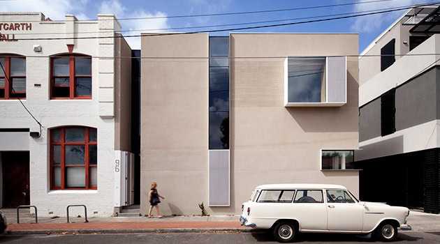 Modern minimalist residential building with clean lines, large glass windows, and geometric design.