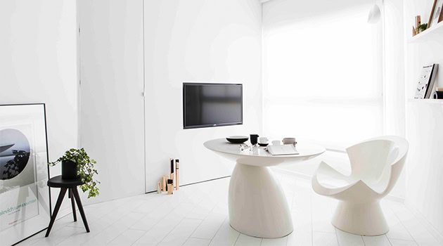 Minimalist white interior with sleek modern furniture and wall-mounted flat-screen TV, emphasizing contemporary architecture and stylish home design.