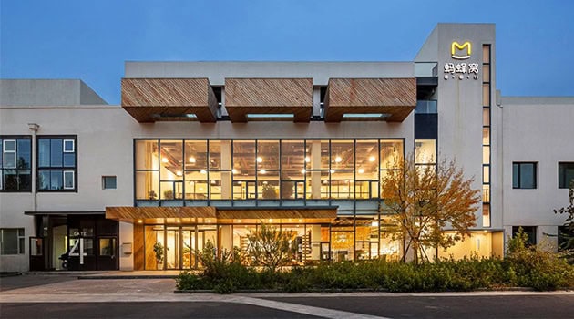 Modern commercial building with large glass windows and contemporary architectural design, featuring wooden accents and a sleek facade. Ideal for business and retail spaces.