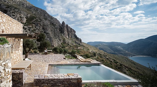 Modern mountain retreat with infinity pool overlooking scenic landscape and rugged cliffs, blending natural elements with contemporary architecture for a luxurious outdoor experience.