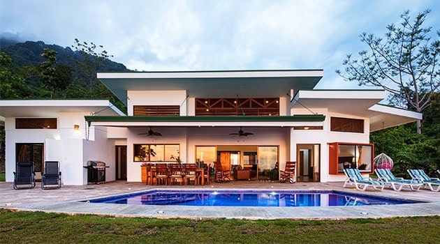 Luxury modern house with a swimming pool, outdoor lounge area, and scenic mountain view, featuring sleek architecture and spacious design for elegant outdoor living.