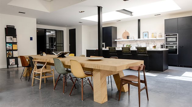 Modern minimalist dining and kitchen interior with sleek black cabinetry, wooden dining table, and contemporary chairs, highlighting stylish home design and open-concept living.
