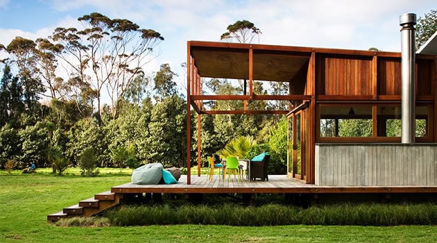 Modern outdoor wooden deck and minimalist house design on lush green landscape, emphasizing contemporary architecture, outdoor living space, and eco-friendly building materials.