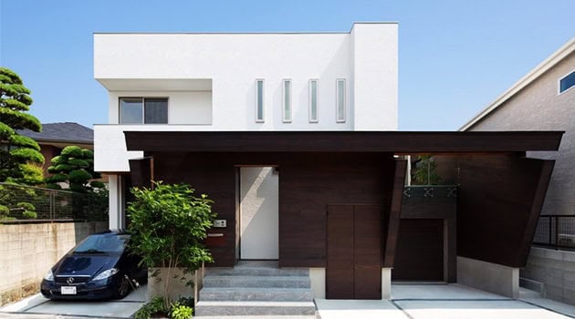 Modern minimalist house with contemporary architecture and unique angular design, featuring clean lines, white facade, and mixed material finishes for stylish curb appeal.