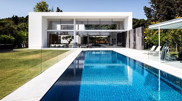 Luxury modern house with sleek design and minimalist architecture featuring a private swimming pool and lush green landscaping.