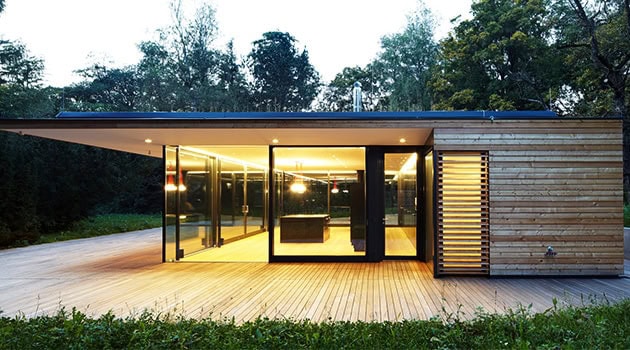 Contemporary modern glass house with sleek design, wooden accents, and large windows showcasing minimalist architecture and innovative residential design elements.