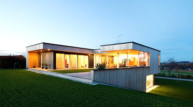 Modern contemporary house with large glass windows and sleek architectural design overlooking landscaped green lawn, showcasing innovative architecture and stylish home exterior.