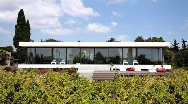 Contemporary modern glass house with sleek architectural design and panoramic views, surrounded by lush greenery and vibrant landscaping. Perfect example of minimalist luxury architecture.
