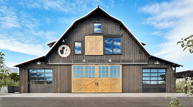 Stylish modern barn with wooden exterior, large windows, and garage doors, ideal for rustic architecture and farmhouse design.