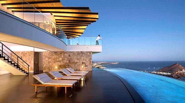 Contemporary luxury house with infinity pool and ocean view, modern architectural design, outdoor lounging area, stylish wooden accents, and sleek glass railing, perfect for upscale modern living.