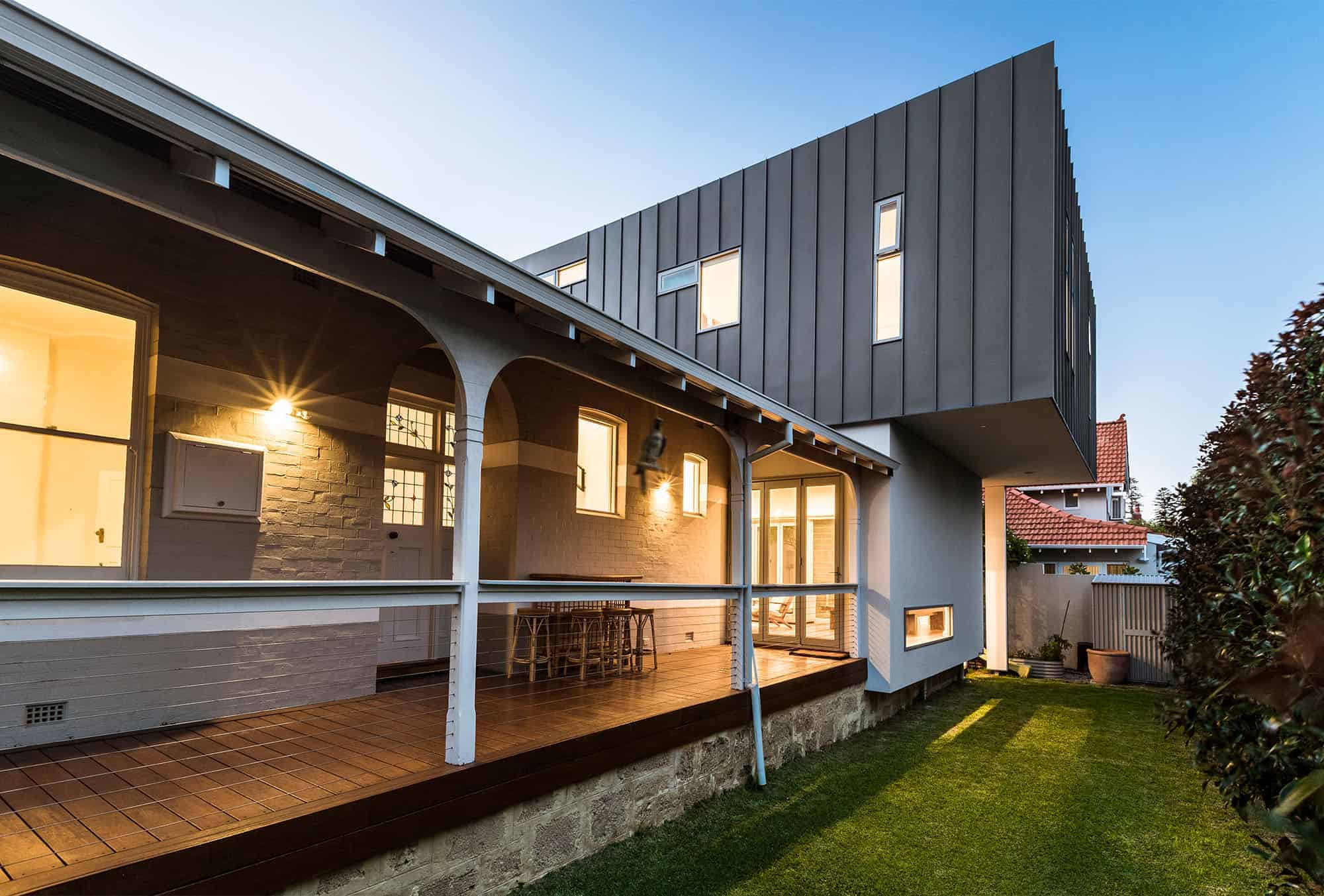 Modern contemporary house exterior with sleek metal siding, cozy porch, and well-maintained backyard featuring lush green lawn and stylish architecture design.