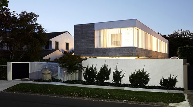Modern minimalist house with sleek concrete and large glass windows, showcasing contemporary architecture design and stylish exterior landscaping.