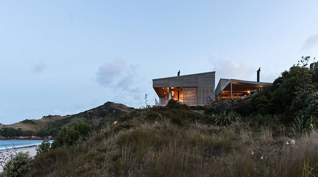 Modern hillside house with contemporary architecture, large glass windows, and sleek design overlooking natural landscape and ocean views.