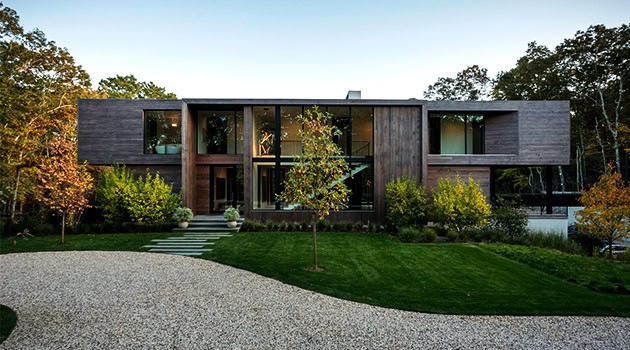 Modern contemporary house with sleek design, large glass windows, and wooden exterior showcasing innovative architecture and art integration.