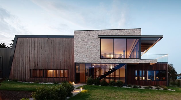 Contemporary modern house with wood, stone, and glass exterior design, large windows, and spacious balcony, showcasing innovative architecture and sleek architectural details.