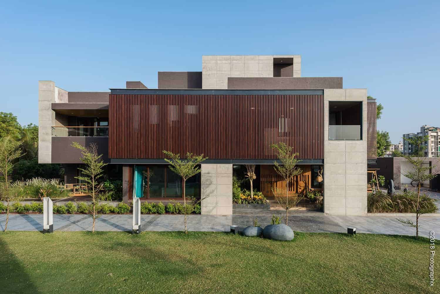 Contemporary modern house with wooden slat facade, concrete structure, and landscaped front yard, showcasing innovative architecture designs, exterior home architecture, and sustainable building materials.