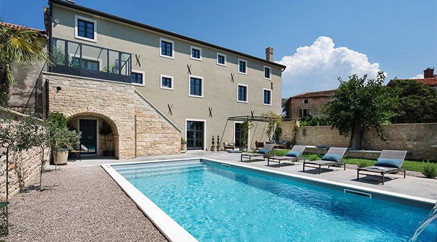 Contemporary house with a private swimming pool, outdoor lounge area, modern architecture, and lush garden, perfect for luxury residential design and outdoor living spaces.