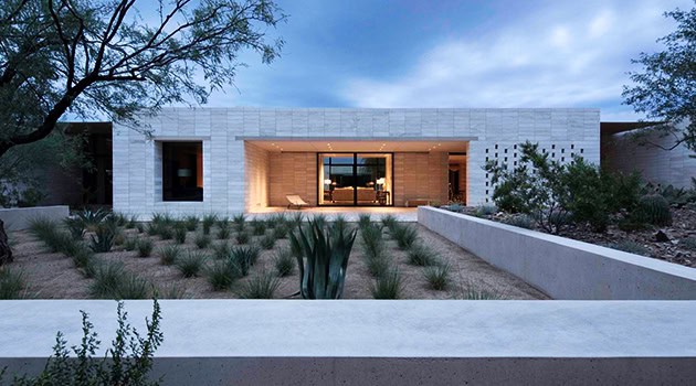 Modern minimalist desert home with sleek white concrete walls and low landscaping, showcasing contemporary architecture design and innovative residential building concepts.