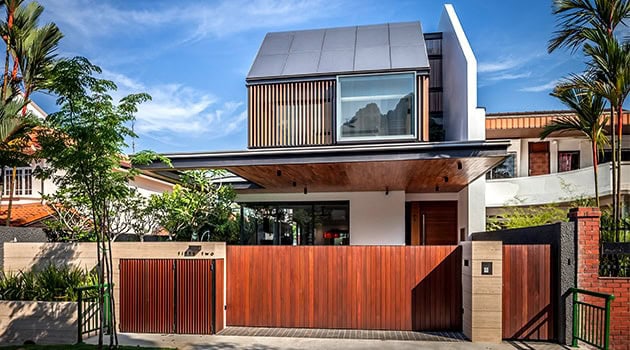 Contemporary modern house with sleek design, wooden accents, large windows, and a spacious gated entrance showcasing innovative architecture and stylish residential design.