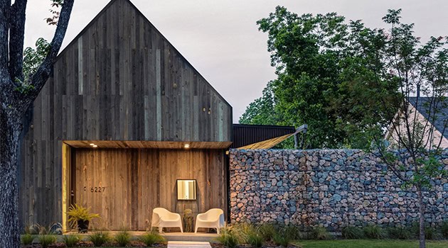 Modern minimalist house with wooden facade and stone wall, showcasing contemporary residential architecture and sustainable design elements.