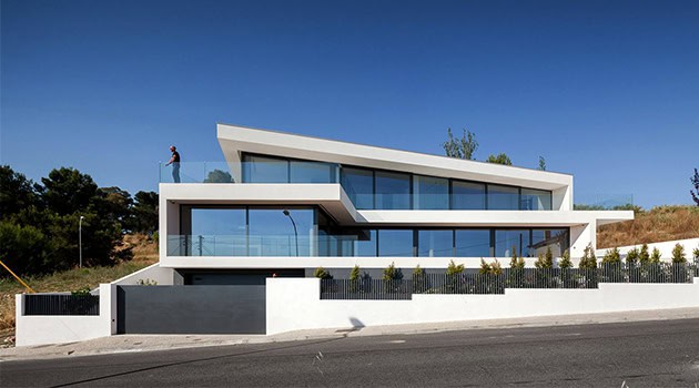 Modern luxury house with sleek geometric design and large glass windows, showcasing contemporary architecture on a clear day.