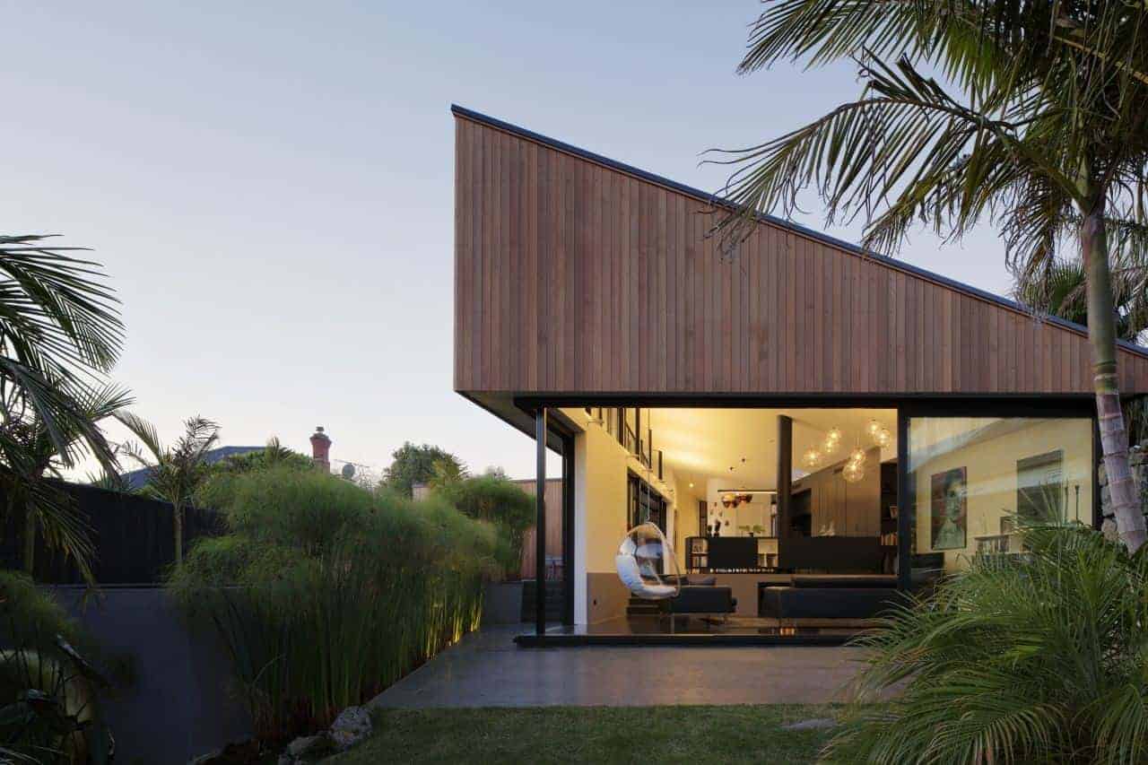 Contemporary modern house with large glass windows, wooden exterior siding, and tropical landscaping, showcasing innovative architecture and stylish interior design.