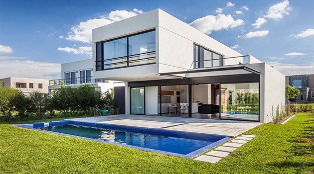 Modern minimalist white two-story villa with large glass windows, outdoor swimming pool, and spacious patio, showcasing contemporary architecture and innovative design.